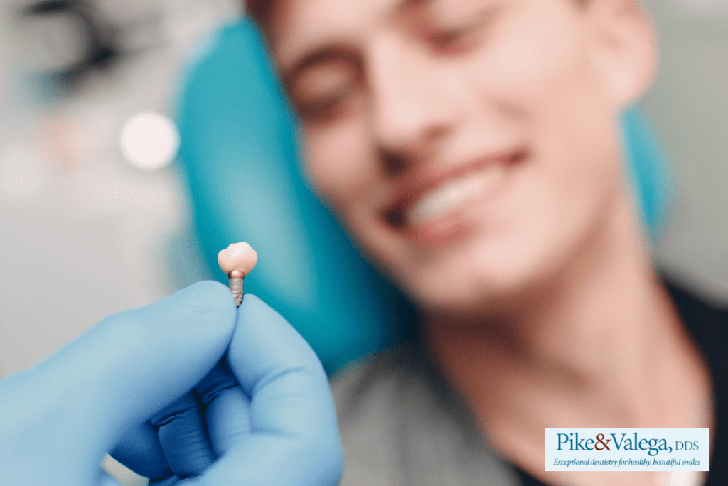 Dentist holding dental implant with smiling patient
